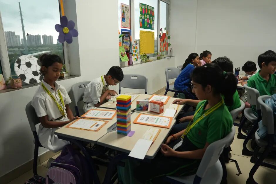 Students in green and white stacking coloured blocks in a classroom