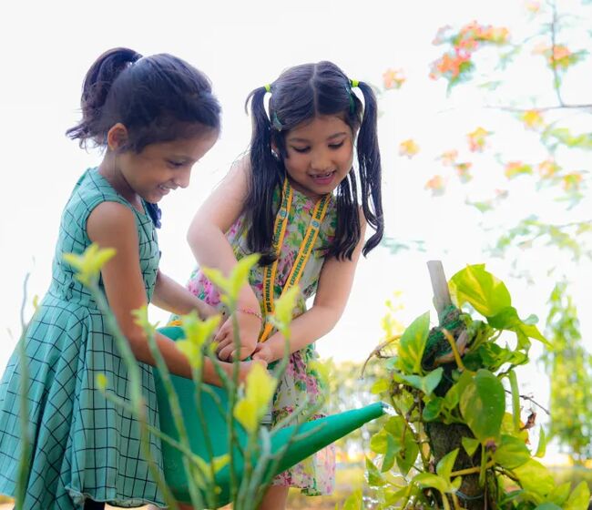 Two young students tending plants in the school garden