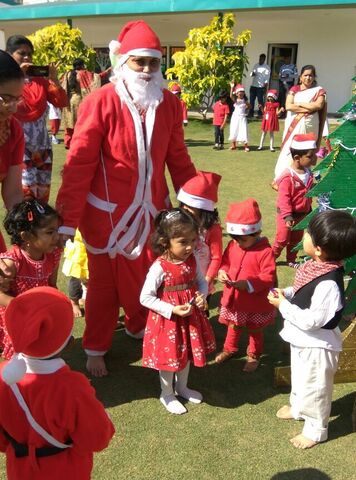 Young children in Santa hats celebrating Christmas with Santa Claus