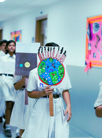 Students in white uniforms parading with hand-made globe masks