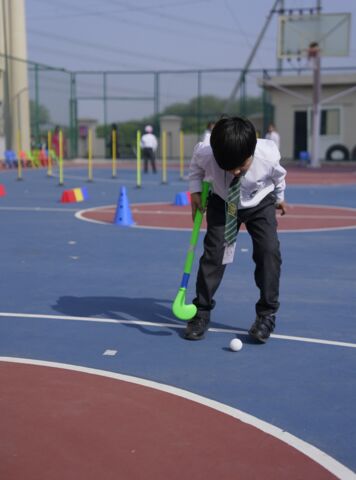 A student practising hockey on the sports court