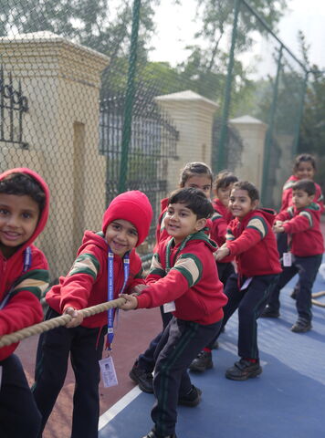 Young students in red jackets pulling a rope in a tug of war